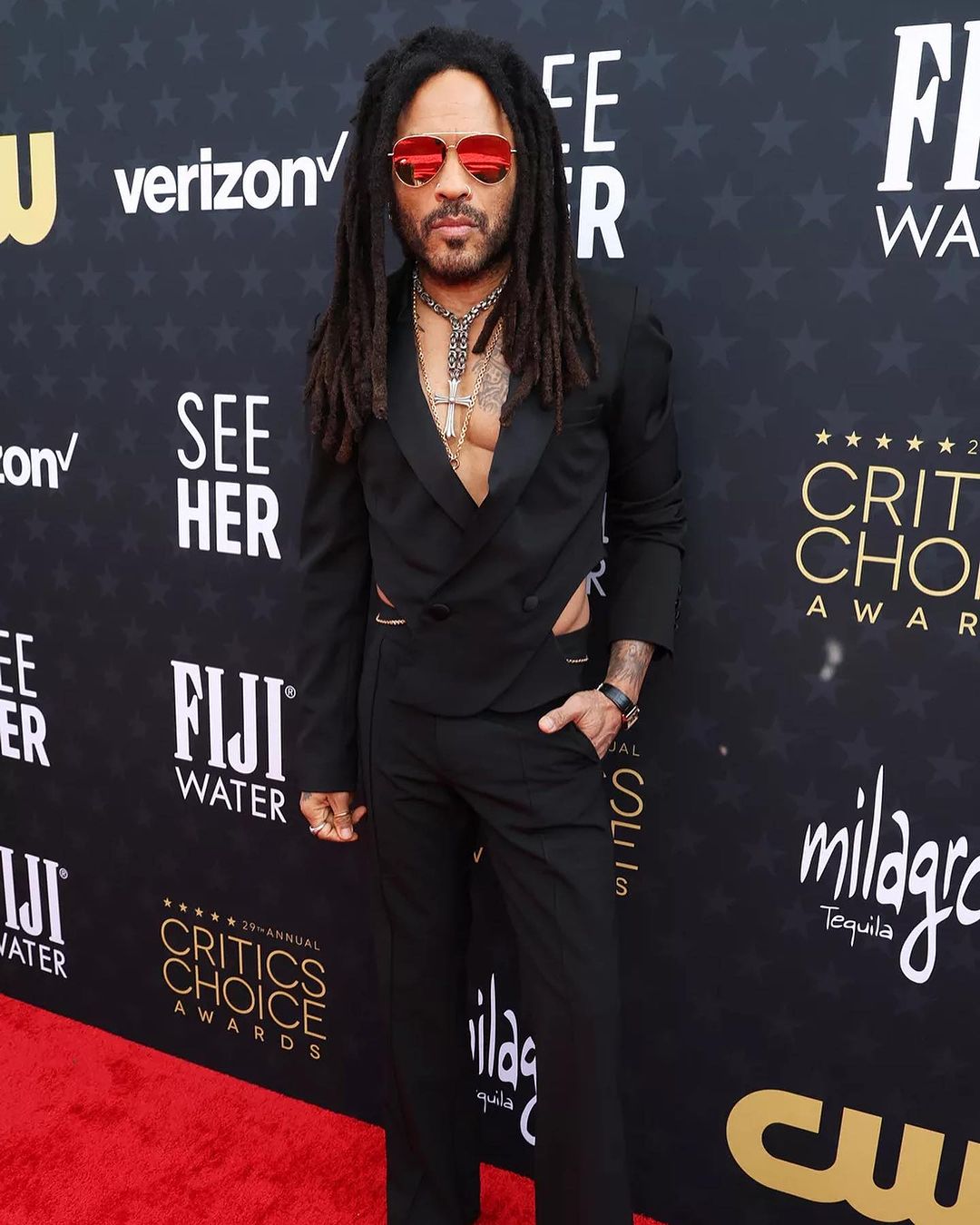 Kravitz Whose “Road to Freedom,” written for “Rustin” nominated for best song, experimented with cutout suiting for the 2024 Critics Choice Awards red carpet. The rock star wore an all-black ensemble that featured a jacket that crossed in the front in a way that showed off hints of skin on the side and back. He topped the outfit off with a stack of necklaces, a thin chain belt, and mirrored shades.