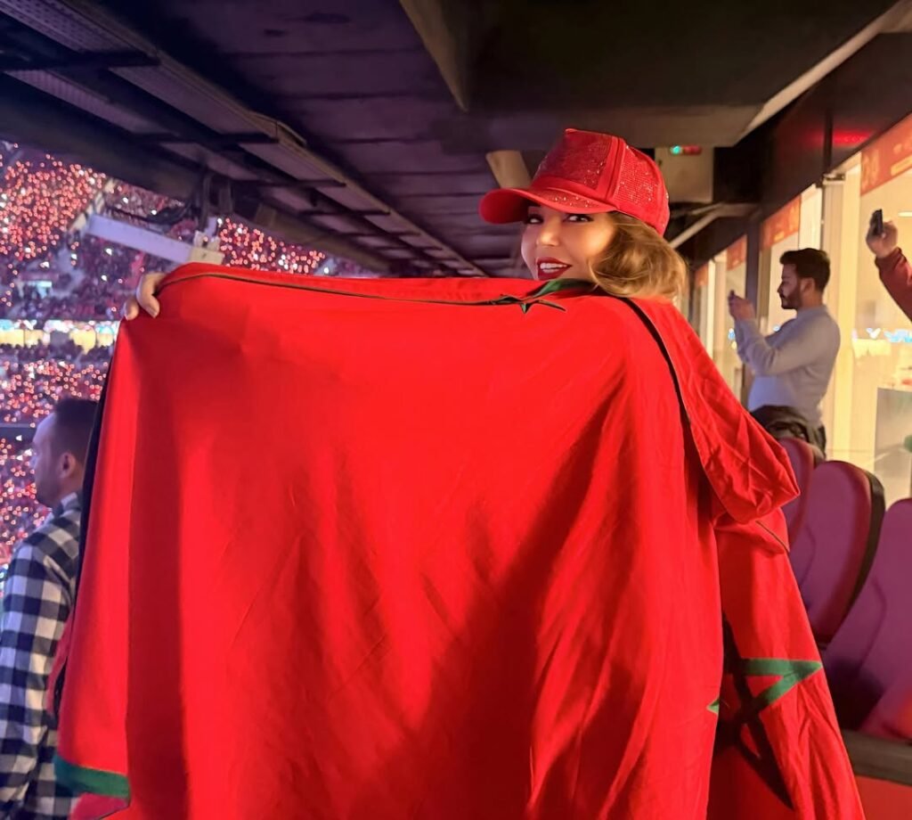 سميرة سعيد تحمل علم المغرب في مدرجات بطولة أمم إفريقيا 2025.